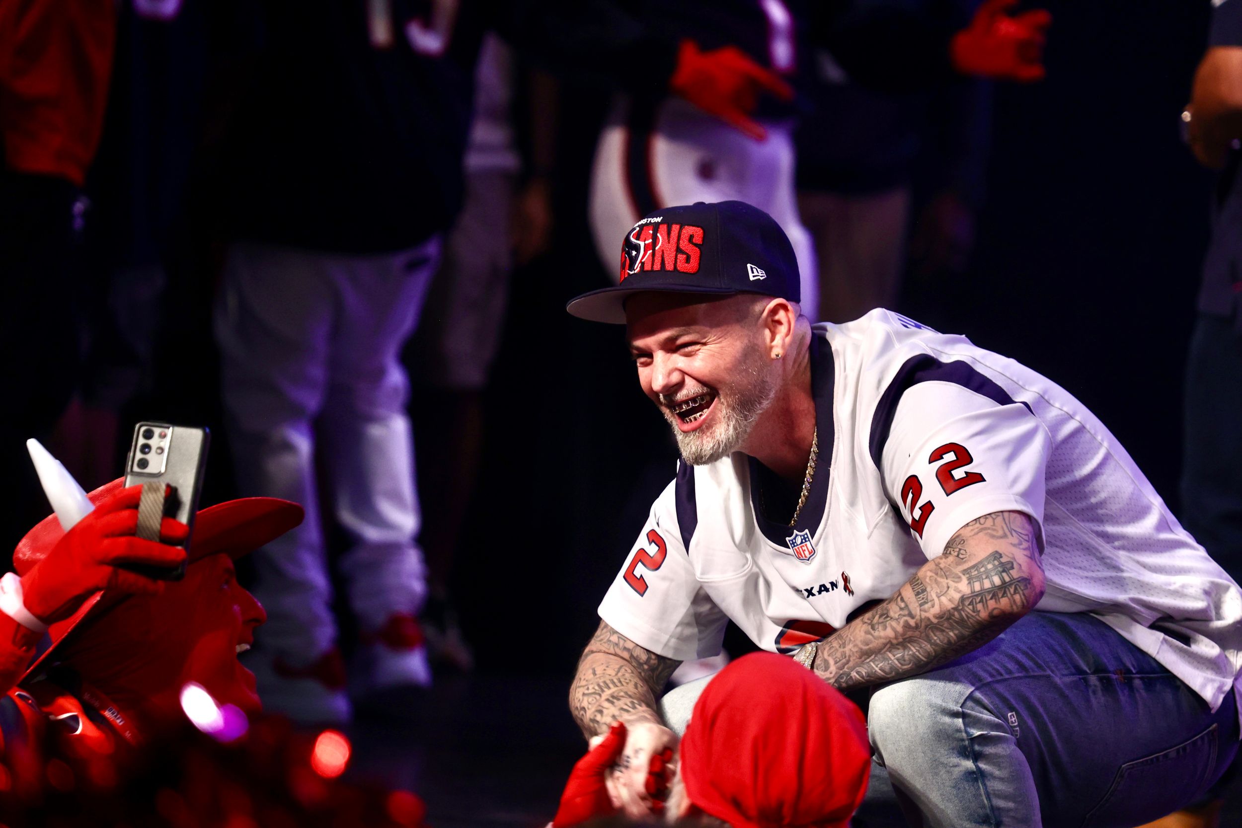 Sports fan in red Sox cap and jersey sits casually at stadium event.