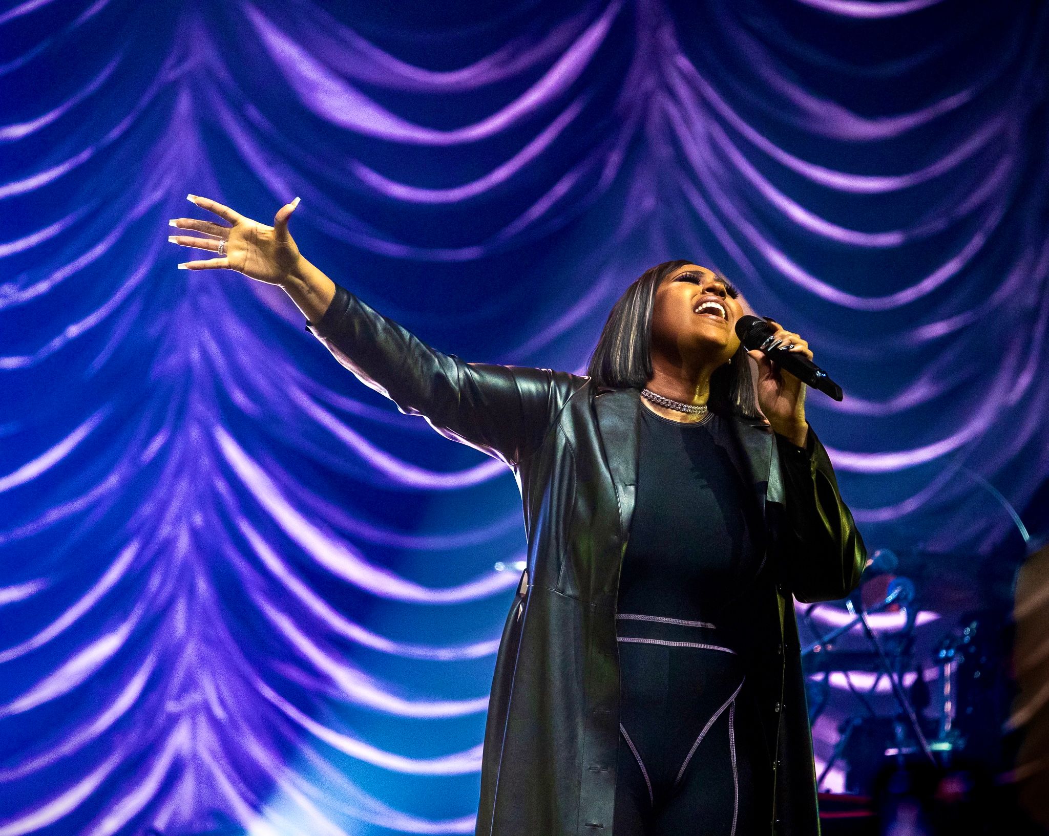 Dramatic concert performance with purple draped backdrop and dramatic stage lighting.