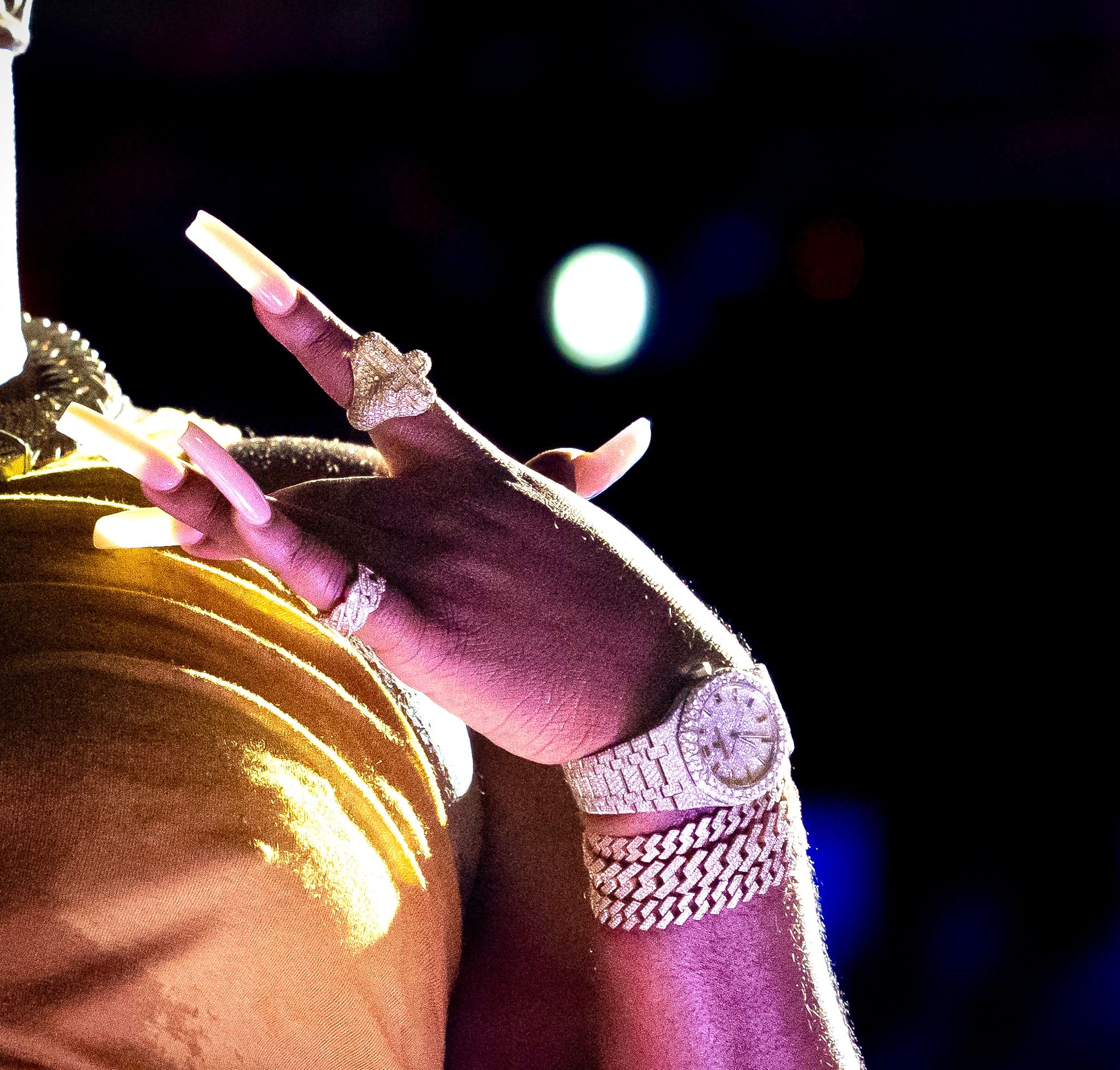 Close-up detail of microphone and bejeweled hand during stage performance.