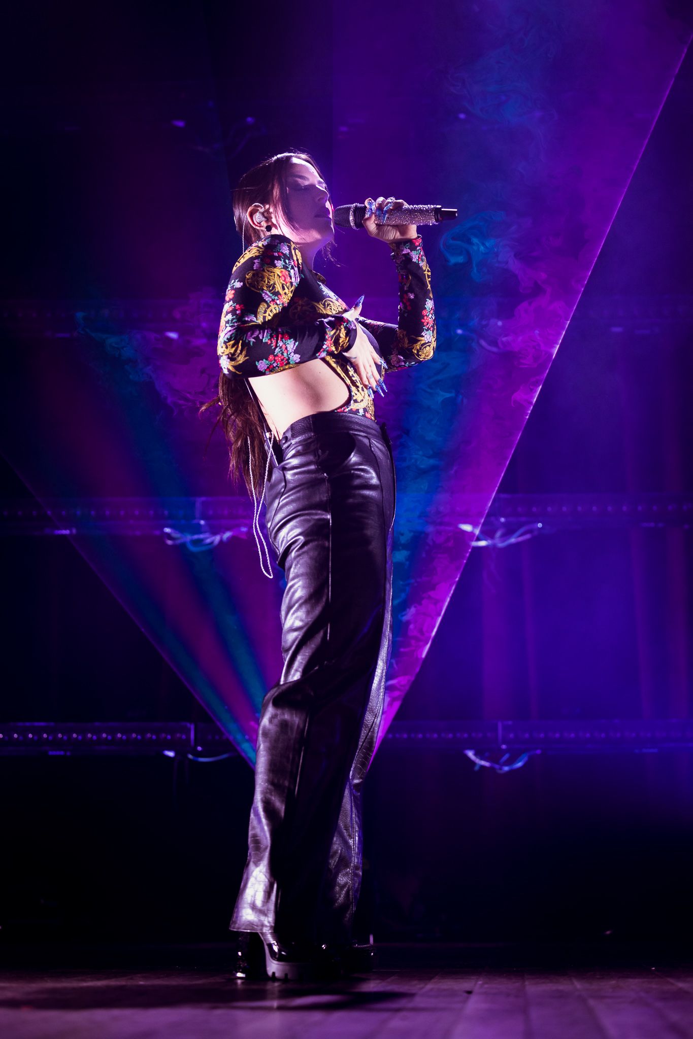 Dynamic concert performance with purple stage lighting and dramatic shadows.