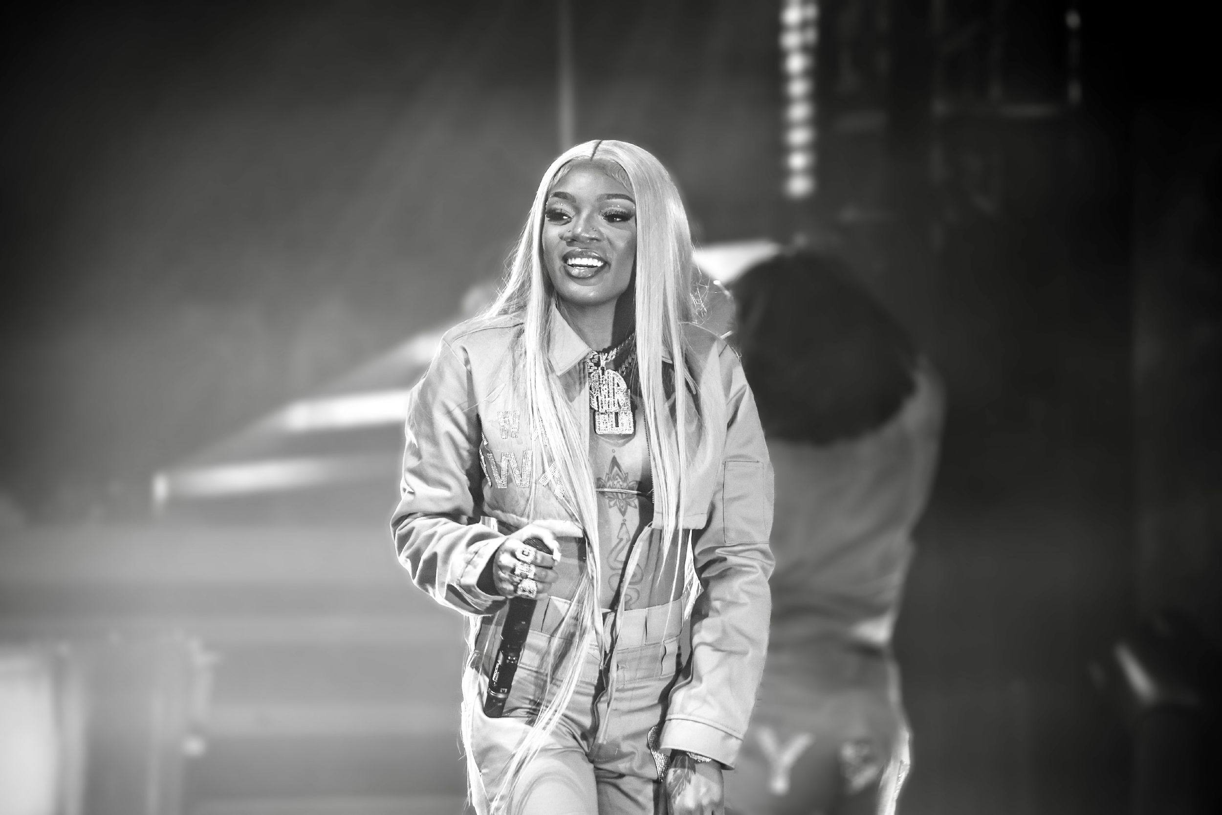 Black and white concert photo of performer in metallic jacket on stage.