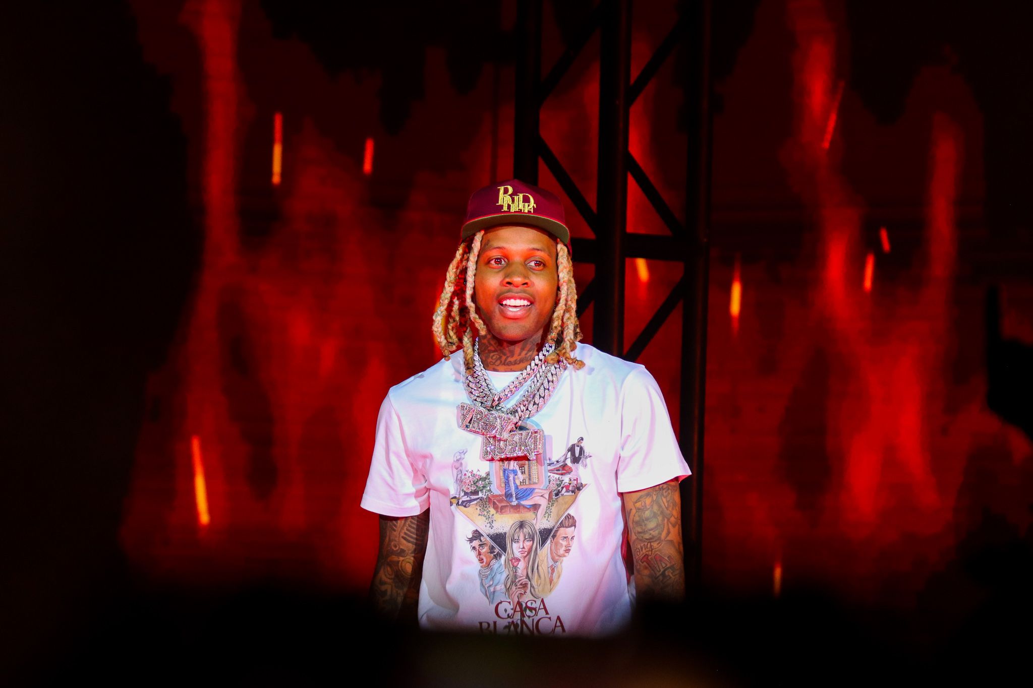 Performer in white t-shirt against dramatic red stage lighting.