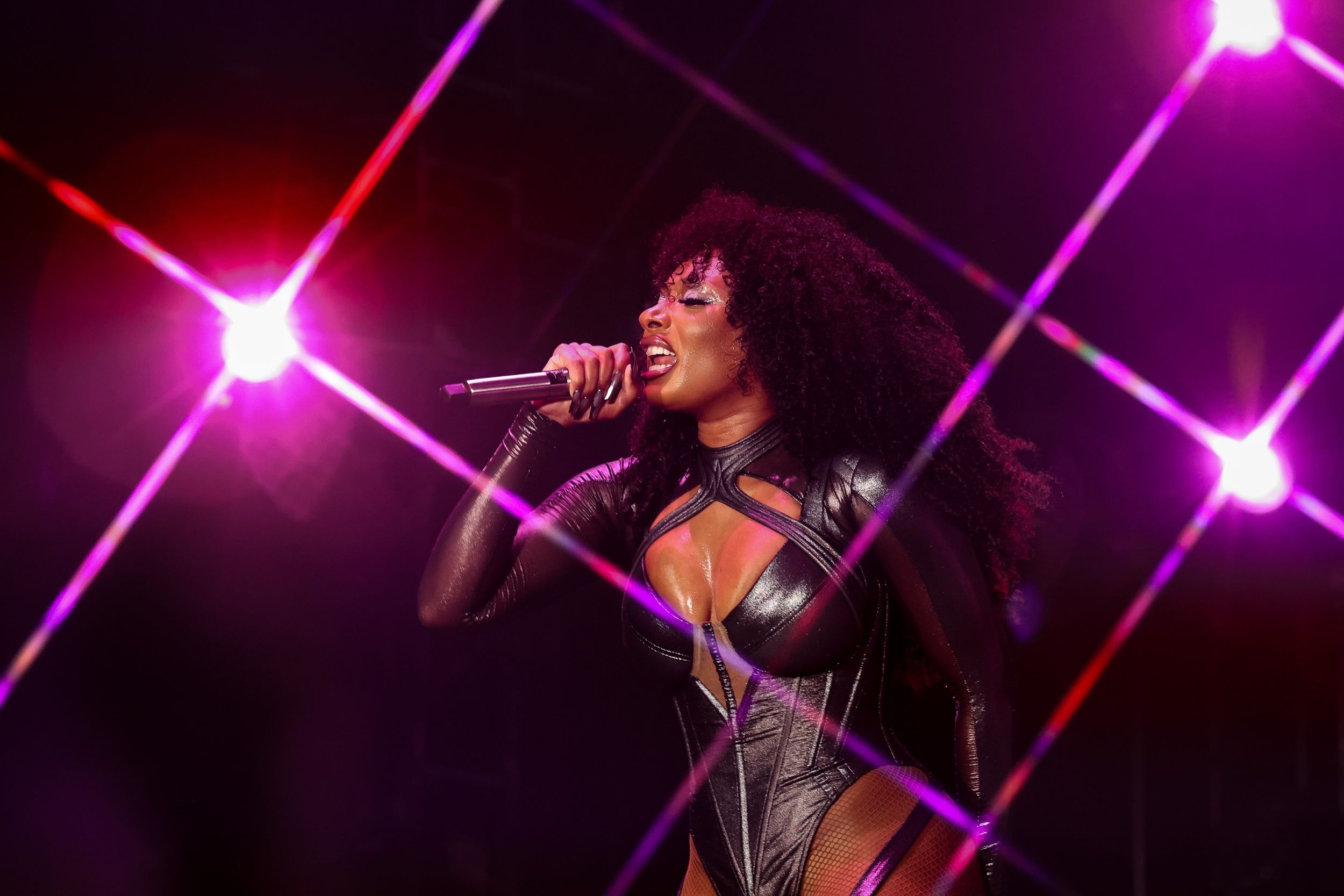 Concert performer singing on stage with dramatic red and pink lighting effects.