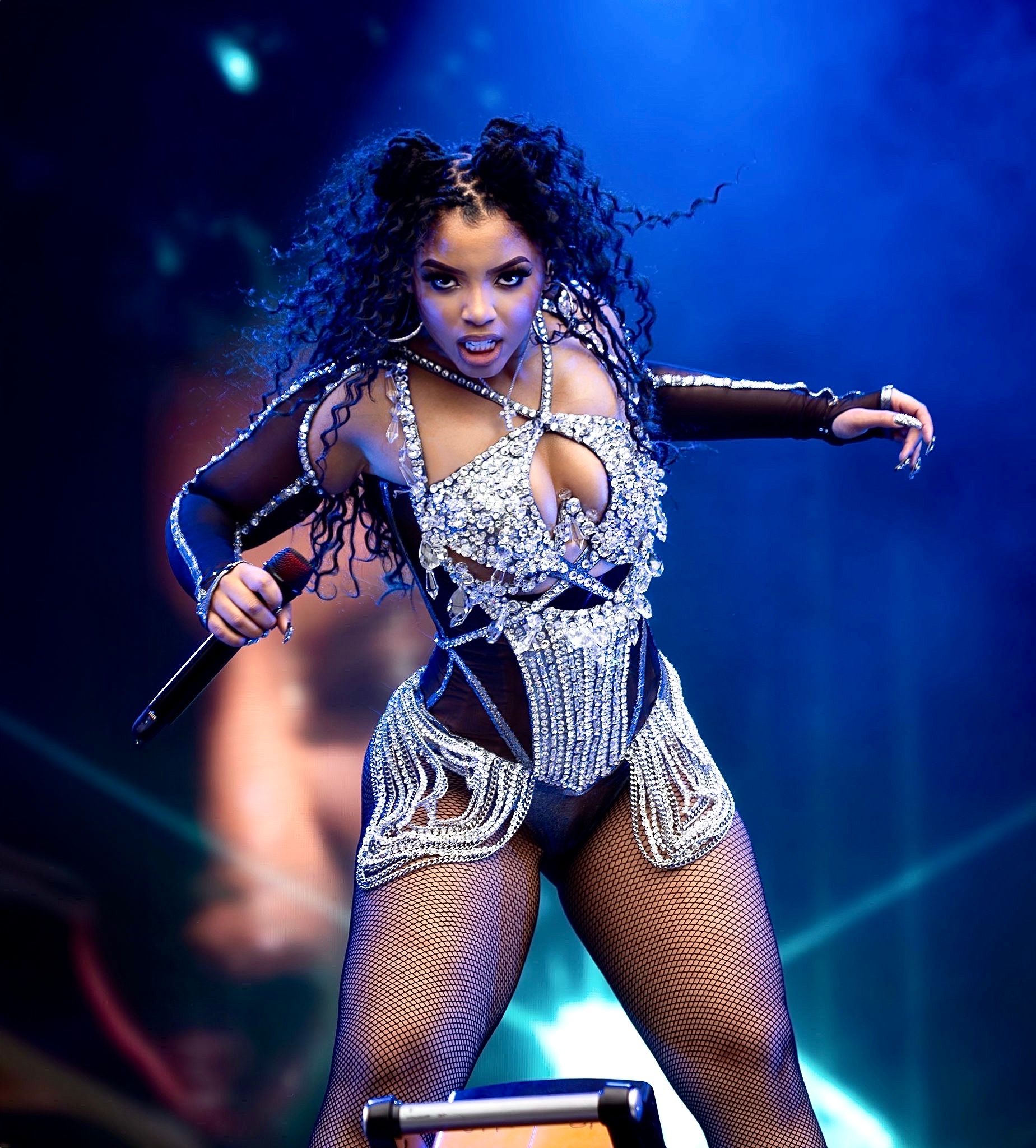 Dynamic stage performance with dancer in silver bodysuit against blue lighting.