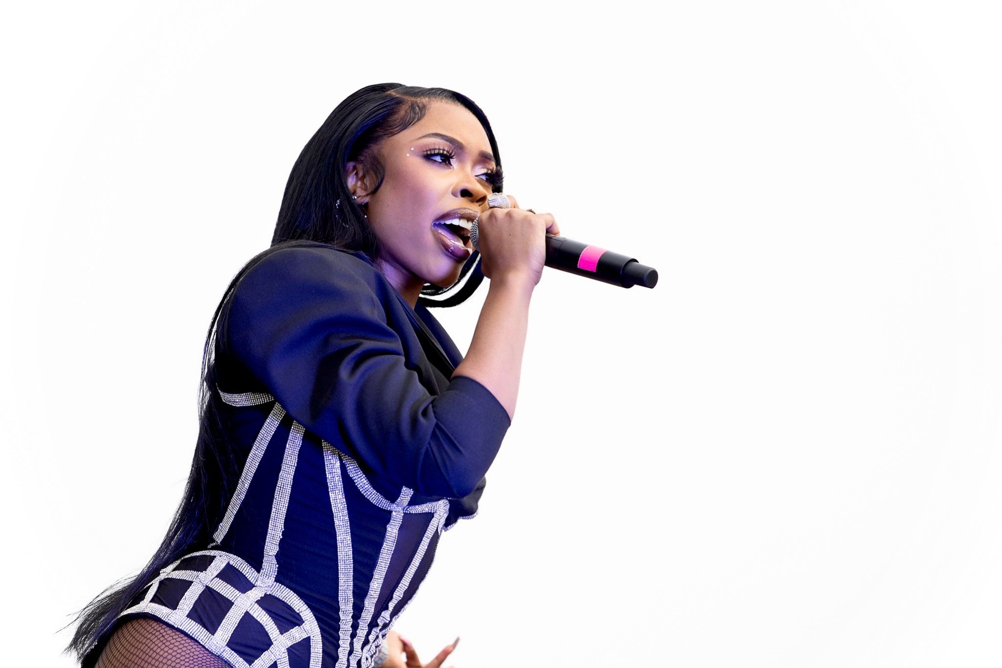 Performer in navy blue costume singing on stage with microphone.