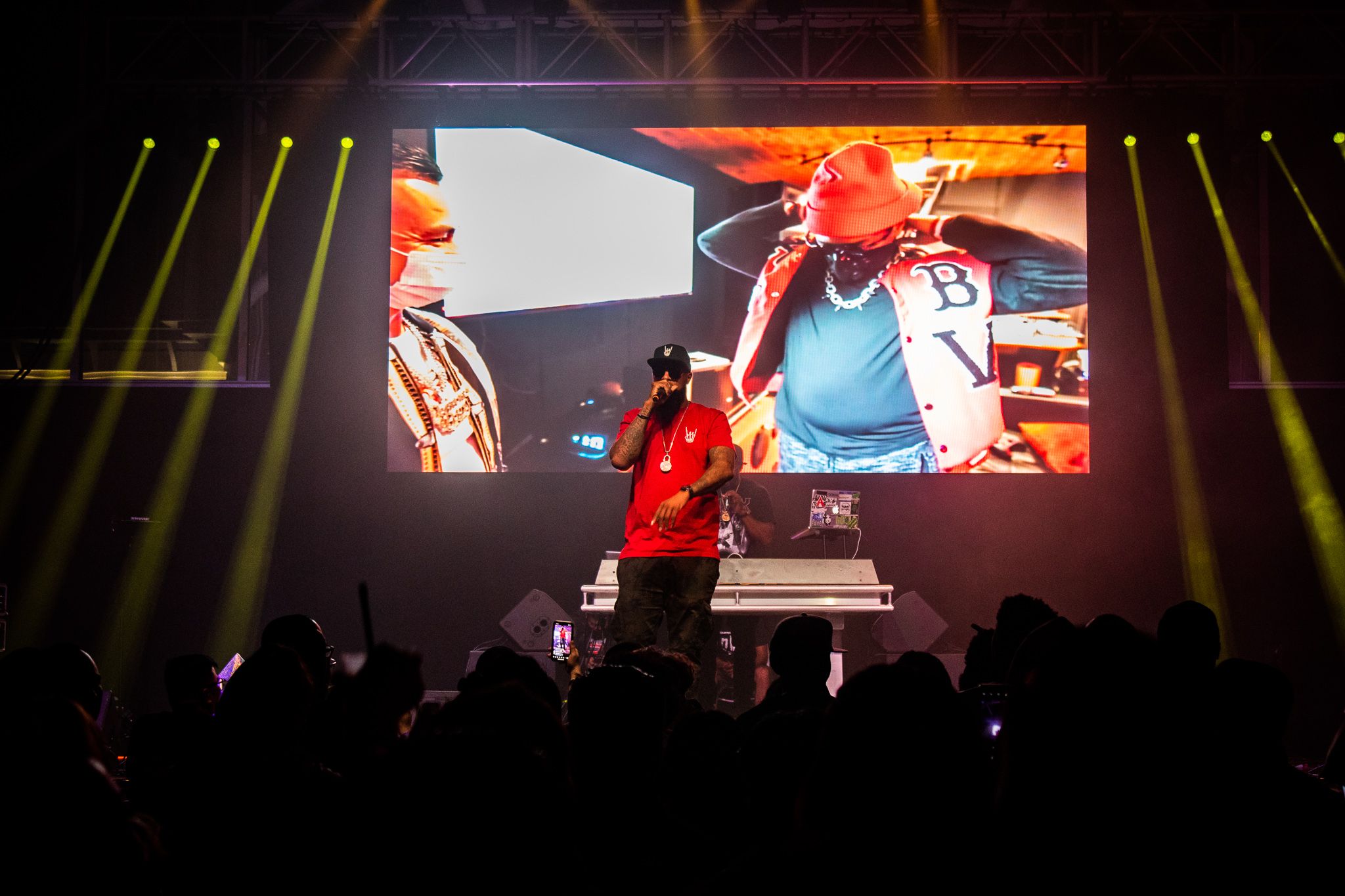 Concert stage with performer in red outfit and large video screen display behind.