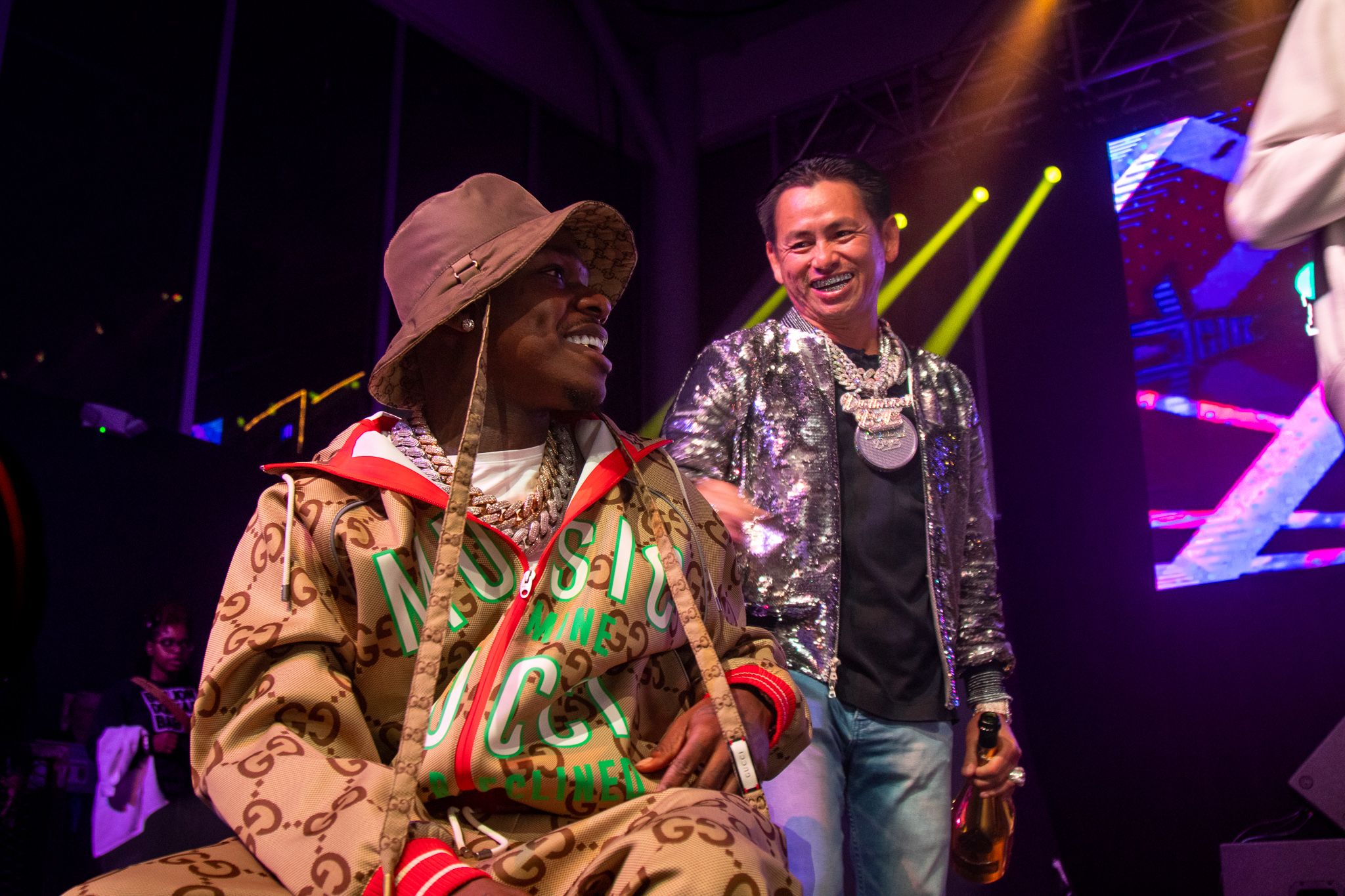 Concert performance scene with colorful stage lighting and performers in designer outfits.