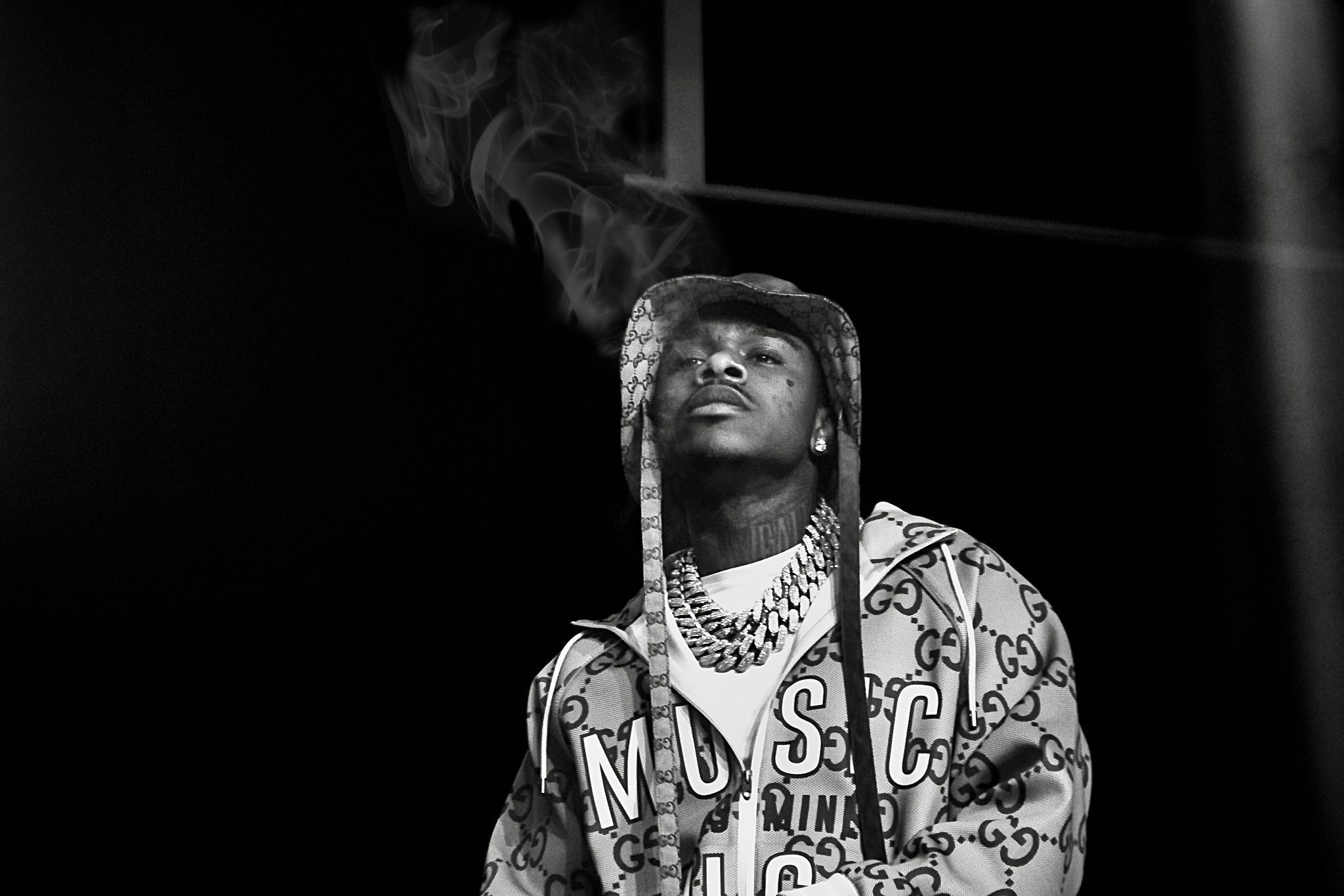 Dramatic black and white portrait of performer wearing chains and patterned clothing on stage.