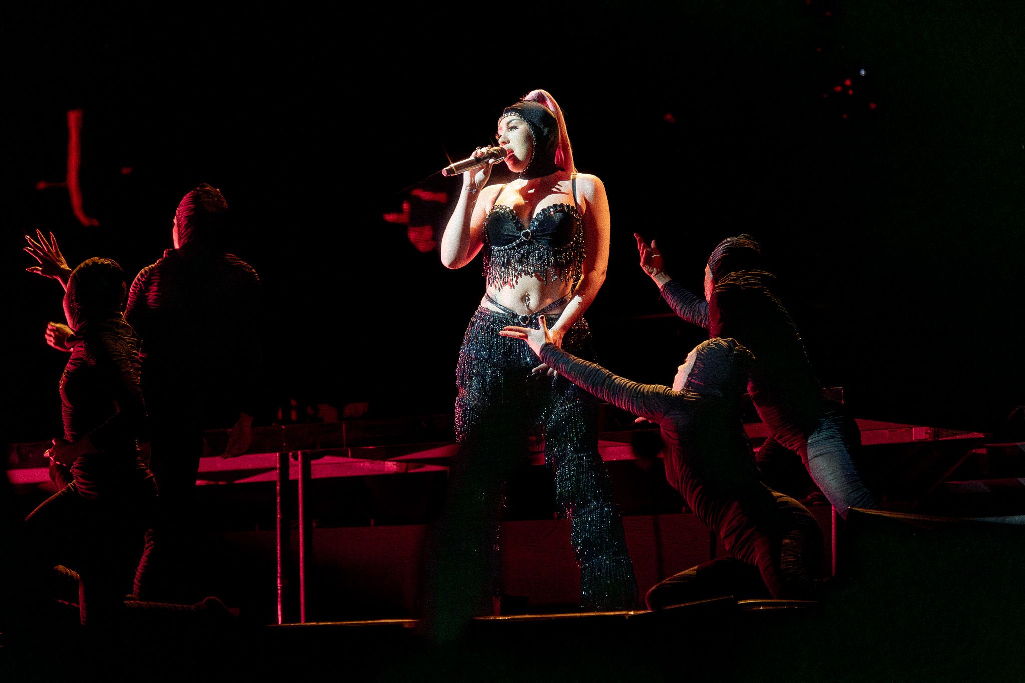 Concert performance with silhouetted backup dancers on dimly lit stage.