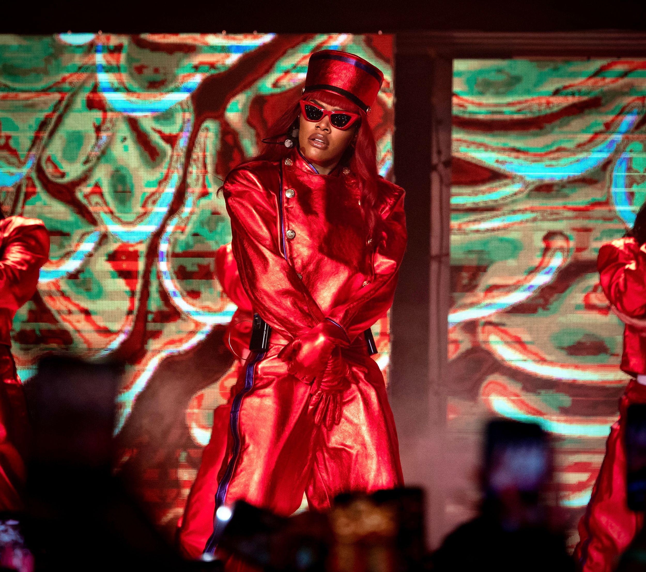Performer in striking red outfit dances during theatrical stage performance.