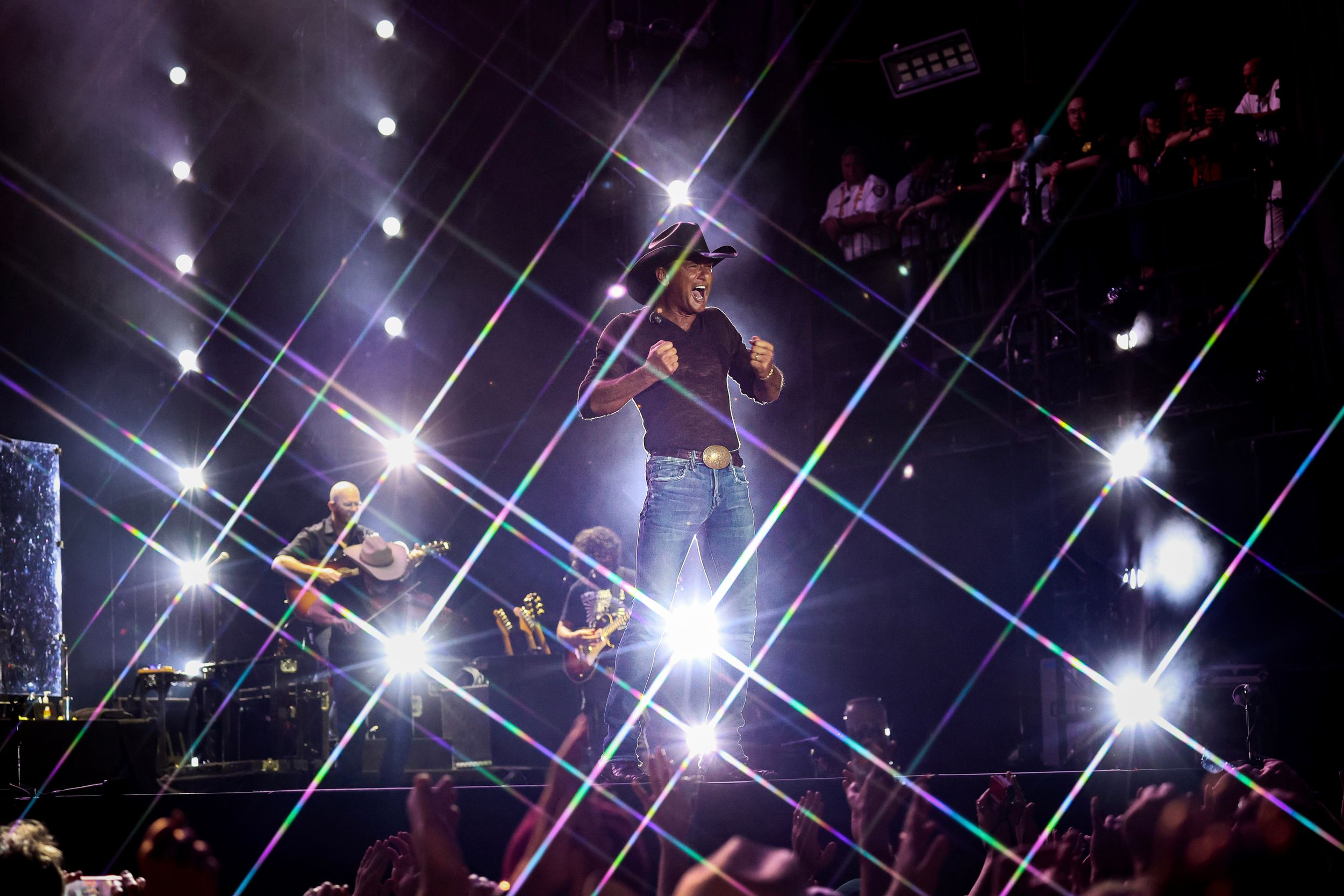 Concert stage illuminated with dramatic star-burst lighting effects and laser beams during performance.