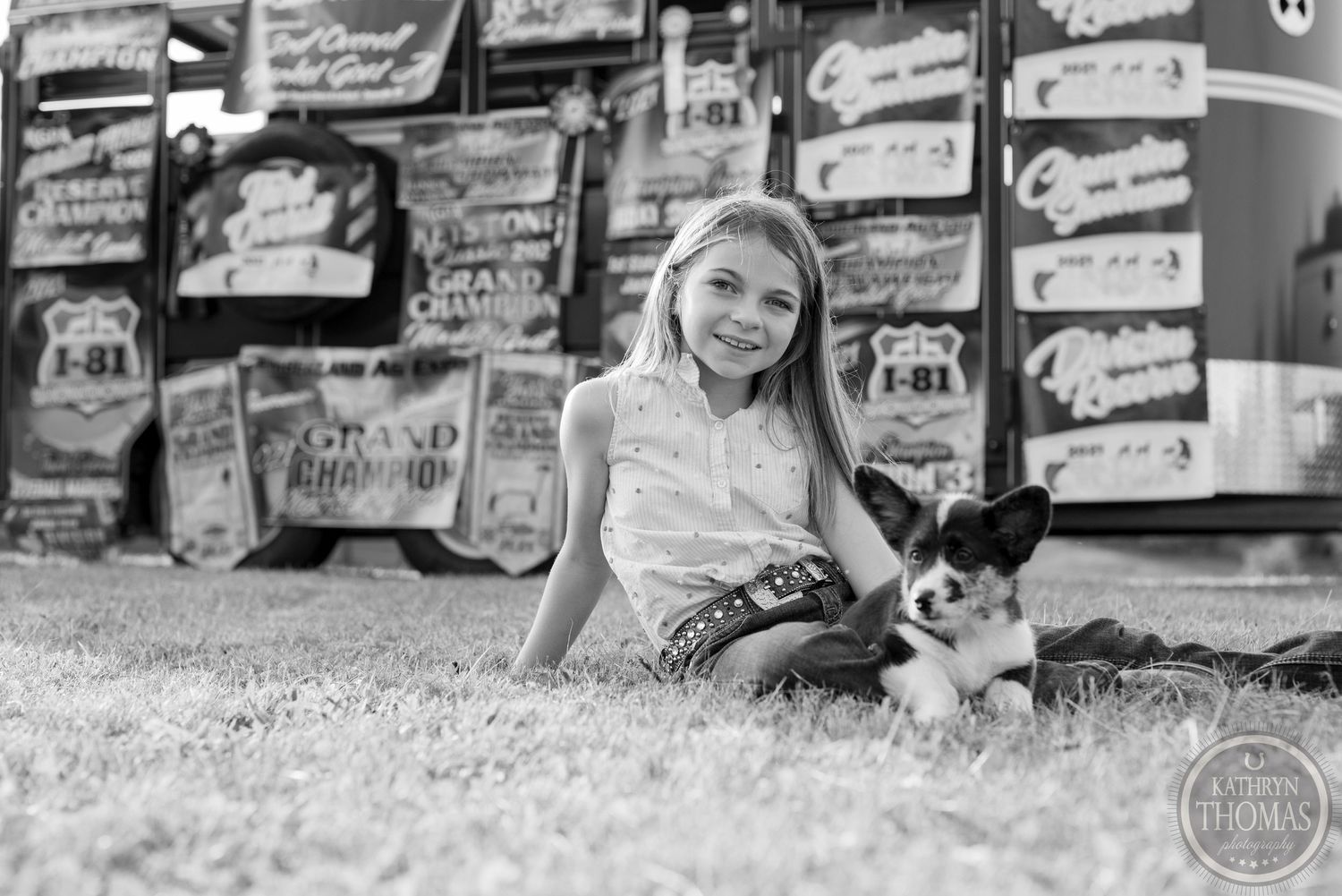 Black and white portrait with person and small dog relaxing by wall of banners.