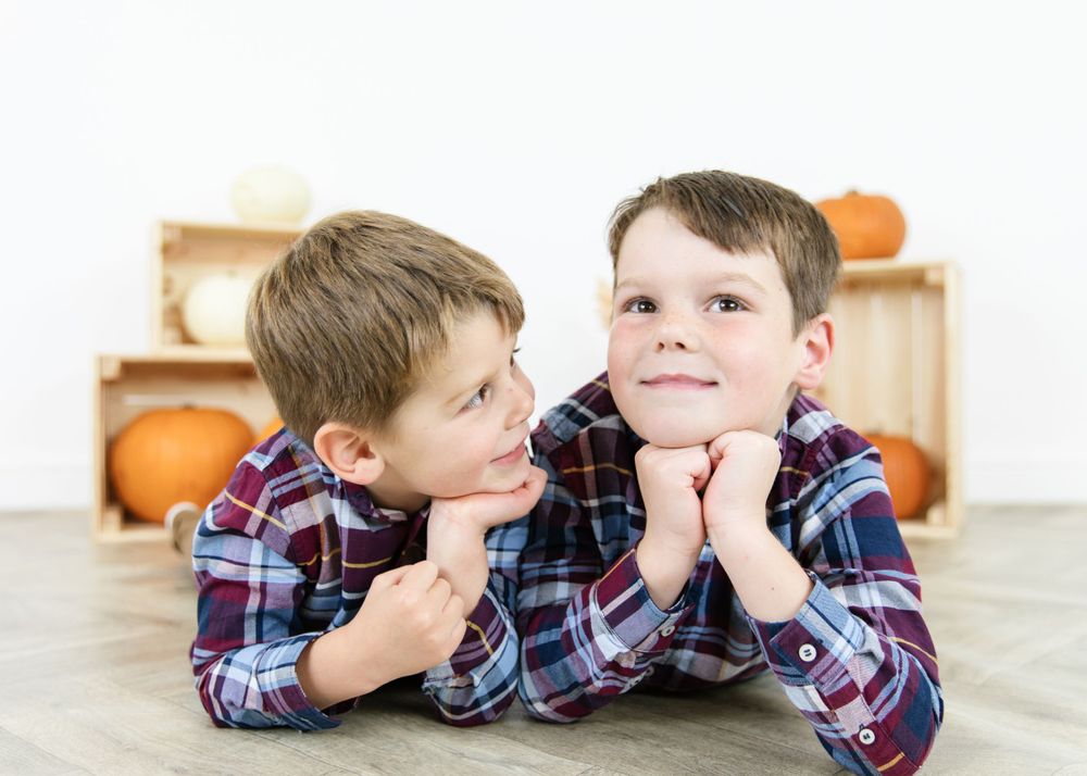 Child in plaid shirt lying down during a relaxed indoor photo session.