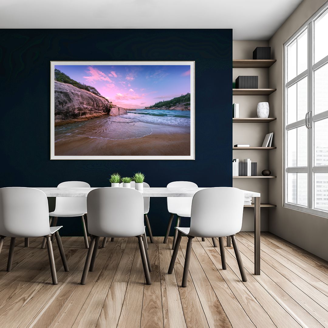 Modern dining room interior with white chairs and large coastal landscape artwork on navy wall.