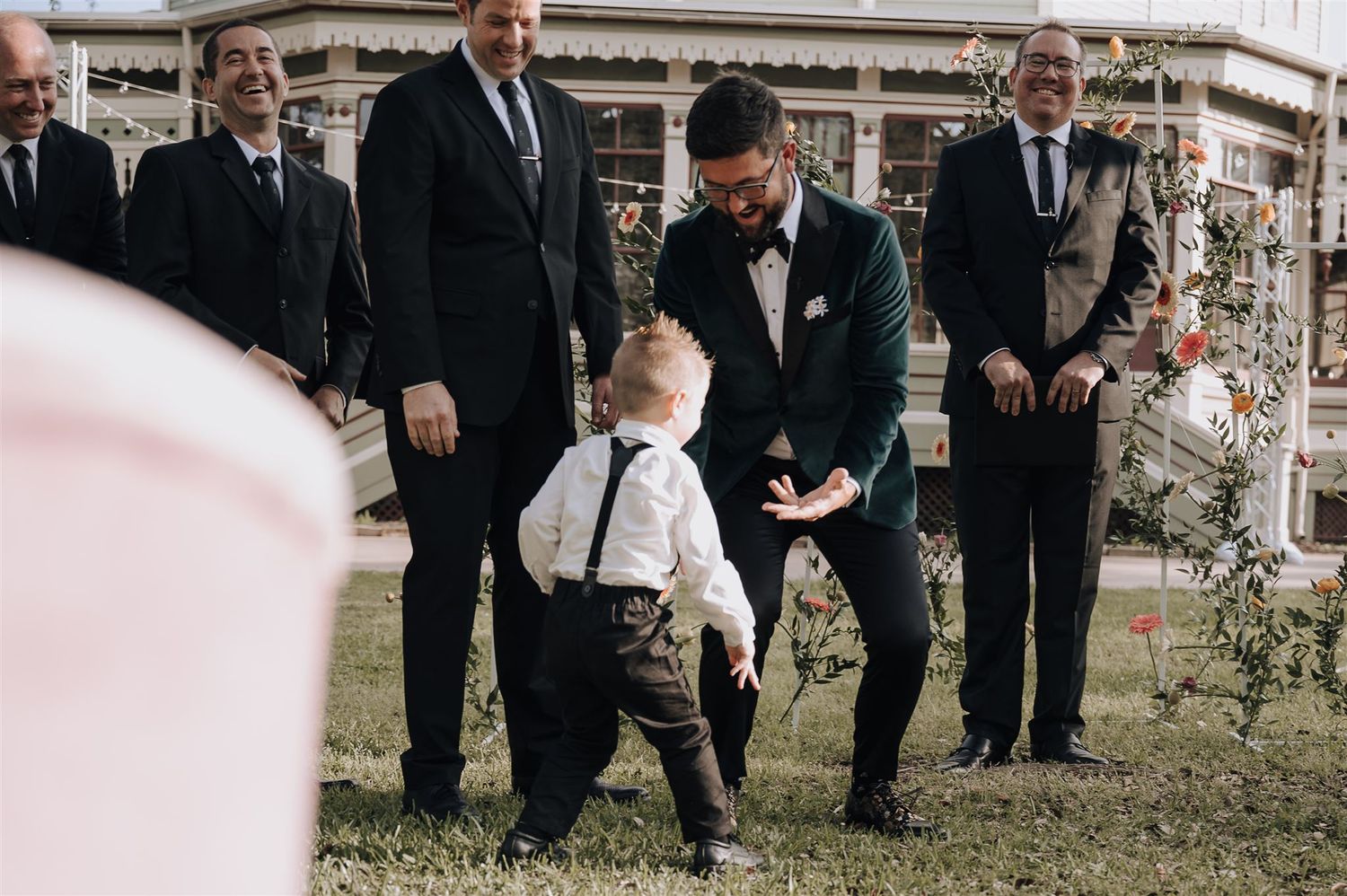 Wedding party members in formal attire gather outdoors during ceremony preparations.