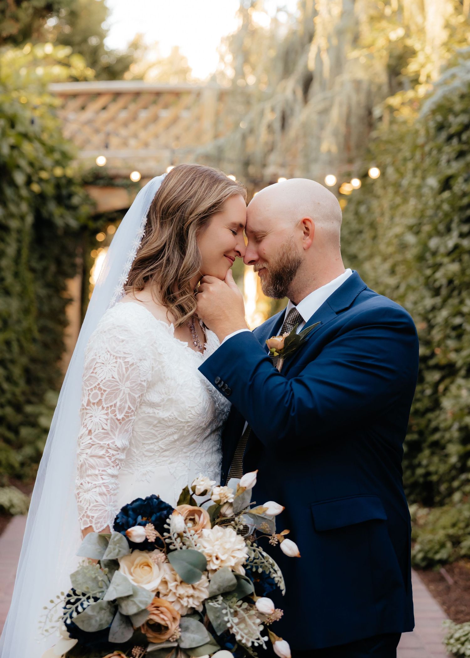 Groom holding brides chin face to face in a garden