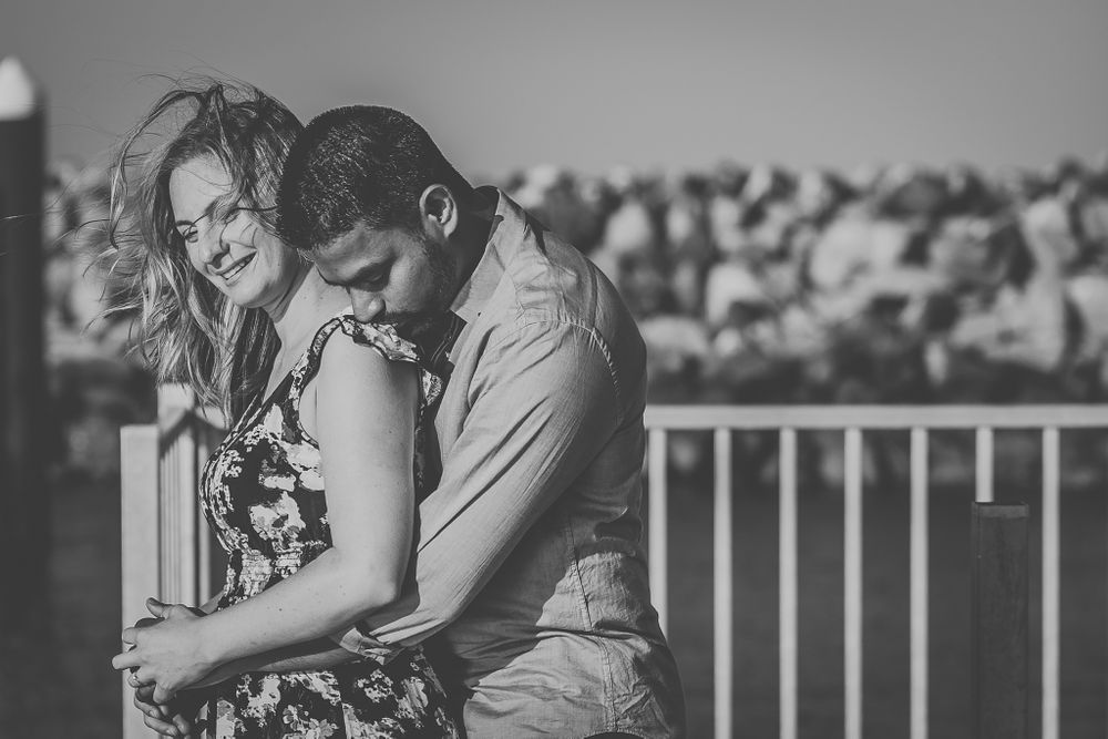 Black and white photo of a couple sharing an intimate moment by a railing.