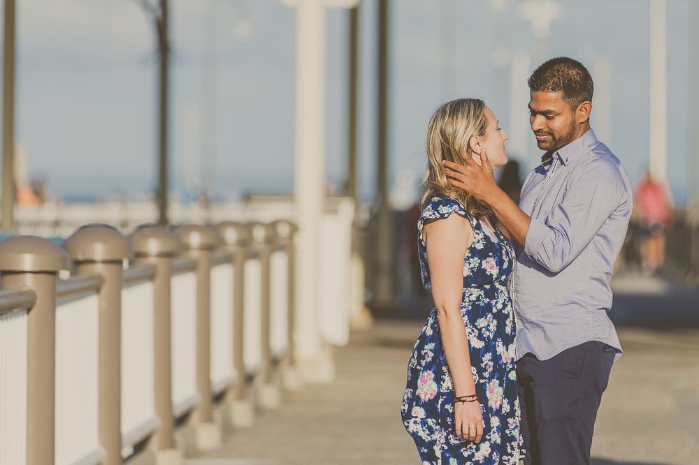 Couple in romantic embrace on oceanfront pier during golden hour.