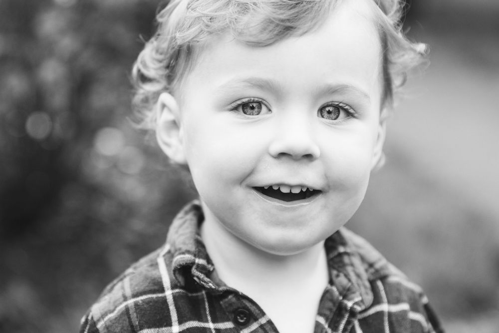Close up black and white portrait of a smiling child in plaid.