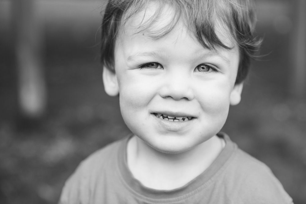 Close-up black and white portrait showing bright smile and joyful expression.