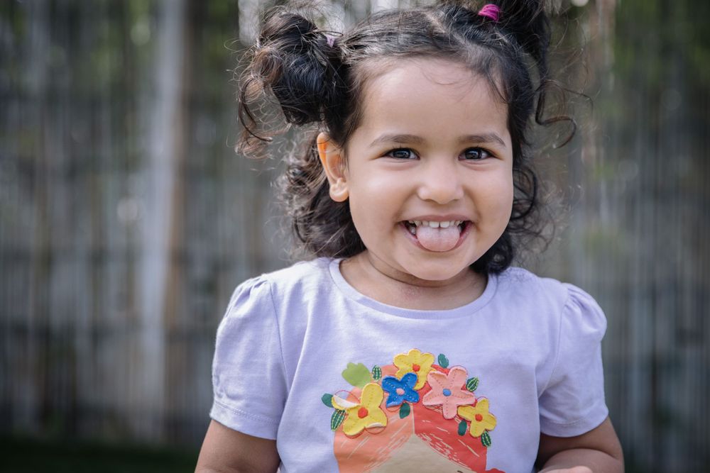 Child wearing t-shirt with rainbow design smiles at camera.