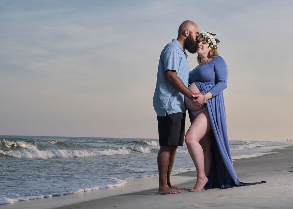 Intimate beachside maternity portrait with waves rolling in during sunset.