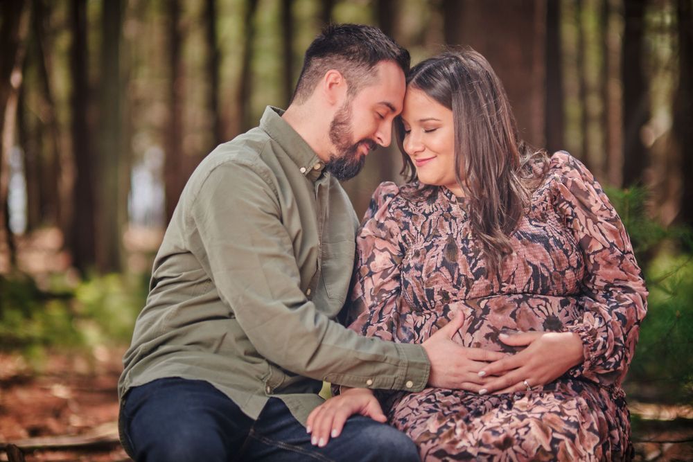 Intimate maternity moment shared between couple in woodland setting.