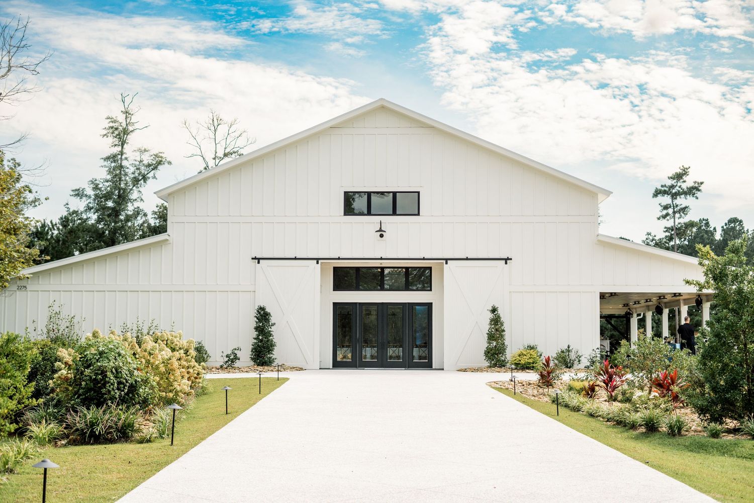 Modern white barn wedding venue with manicured gardens and a grand entrance.