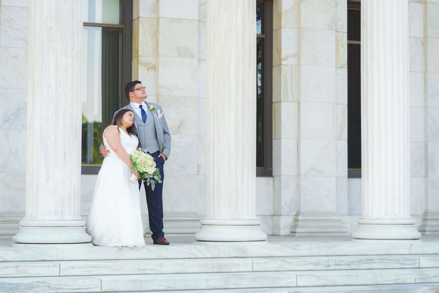 Wedding ceremony backdrop with white architectural columns and natural lighting.