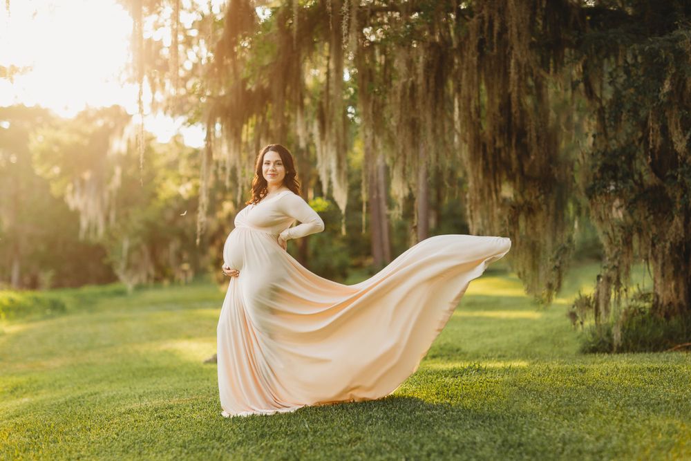 Woman in flowing cream dress twirling in mossy garden during golden hour.