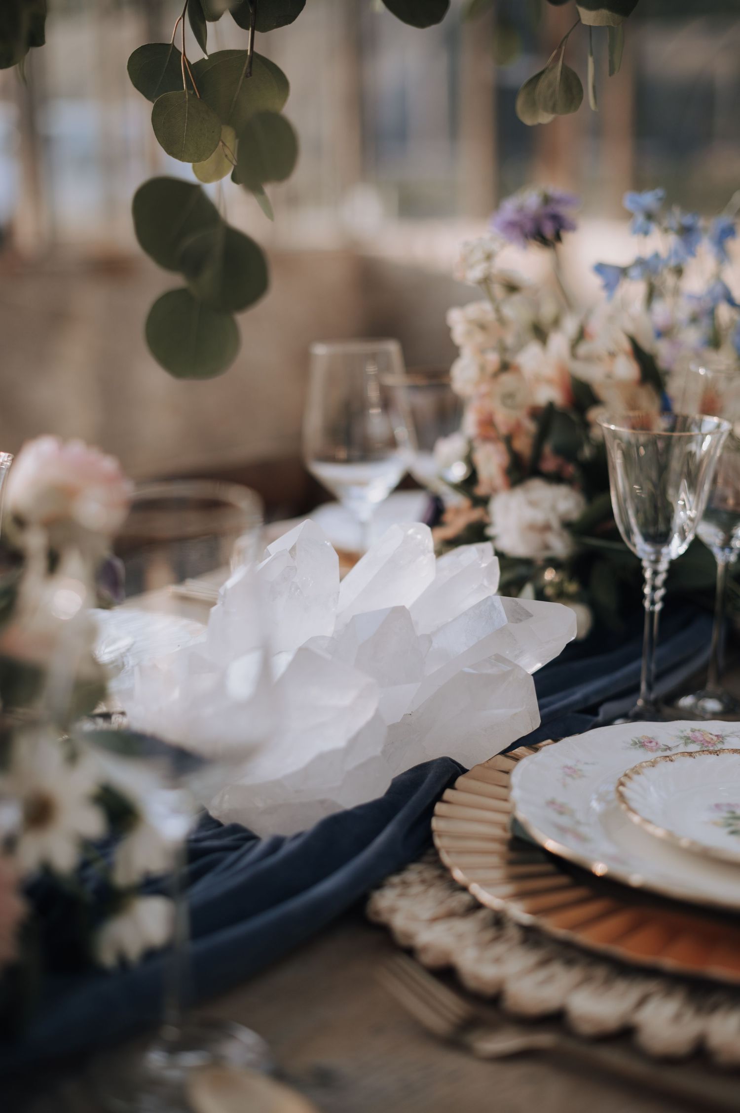 Elegant table setting with navy linens, white napkins, and eucalyptus decor.