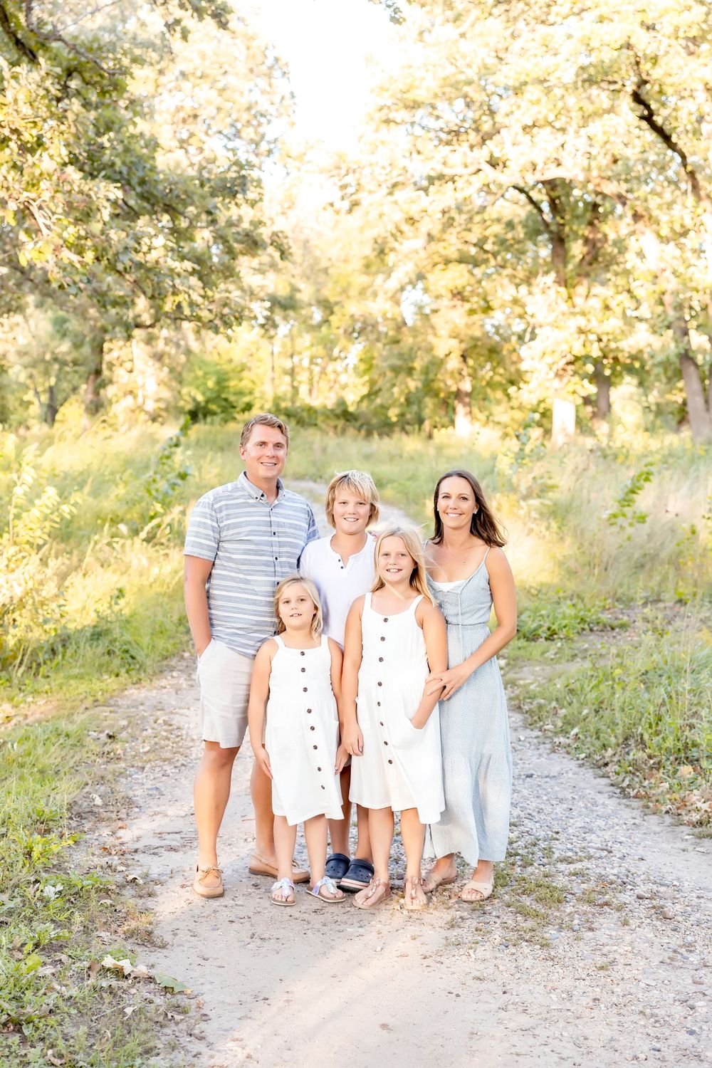 Group portrait on a gravel path with trees creating a warm, glowing backdrop in late afternoon light.