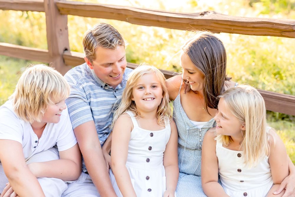 Casual outdoor family portraits with everyone wearing coordinated white and gray outfits.