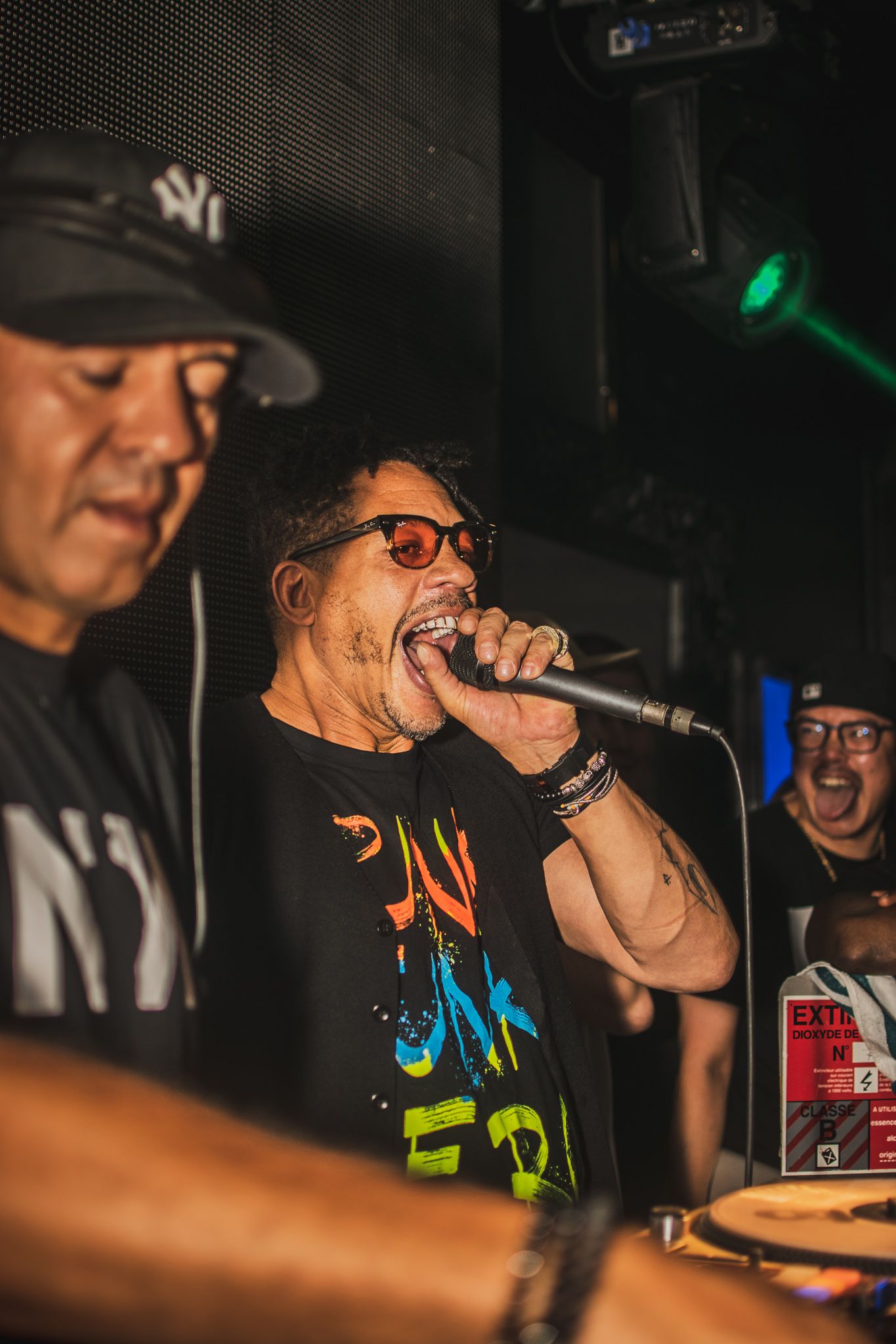 Performer singing into microphone at energetic nightclub performance.