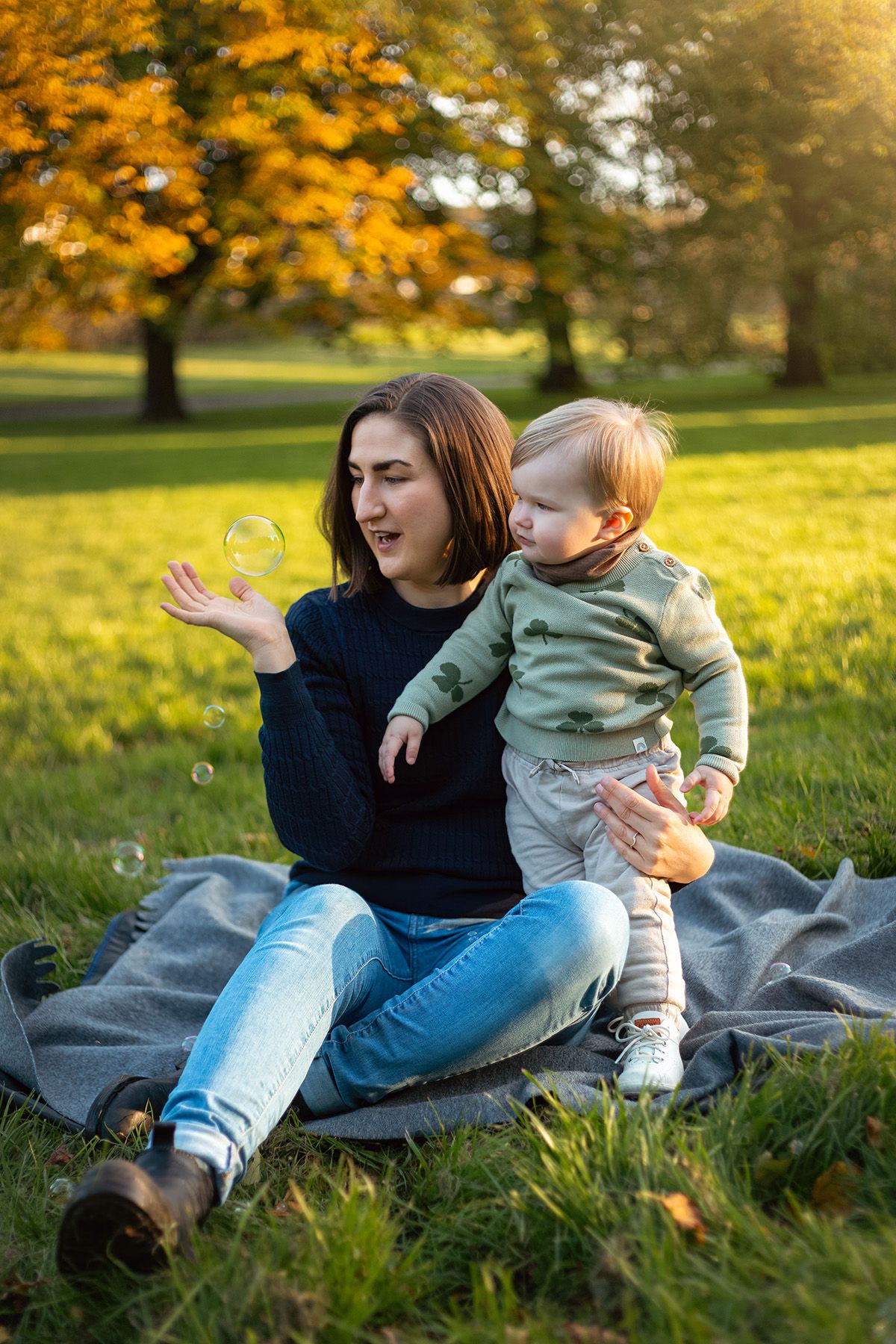 Familjefotografering. Mamma och barn i naturen leker med sopabubblor