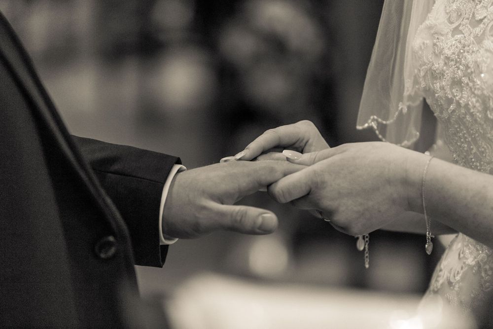 close up of the bride putting a ring on the grooms finger