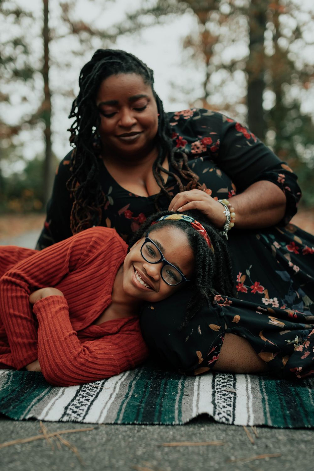 Two people lying on a patterned blanket share a playful moment during an autumn photoshoot.