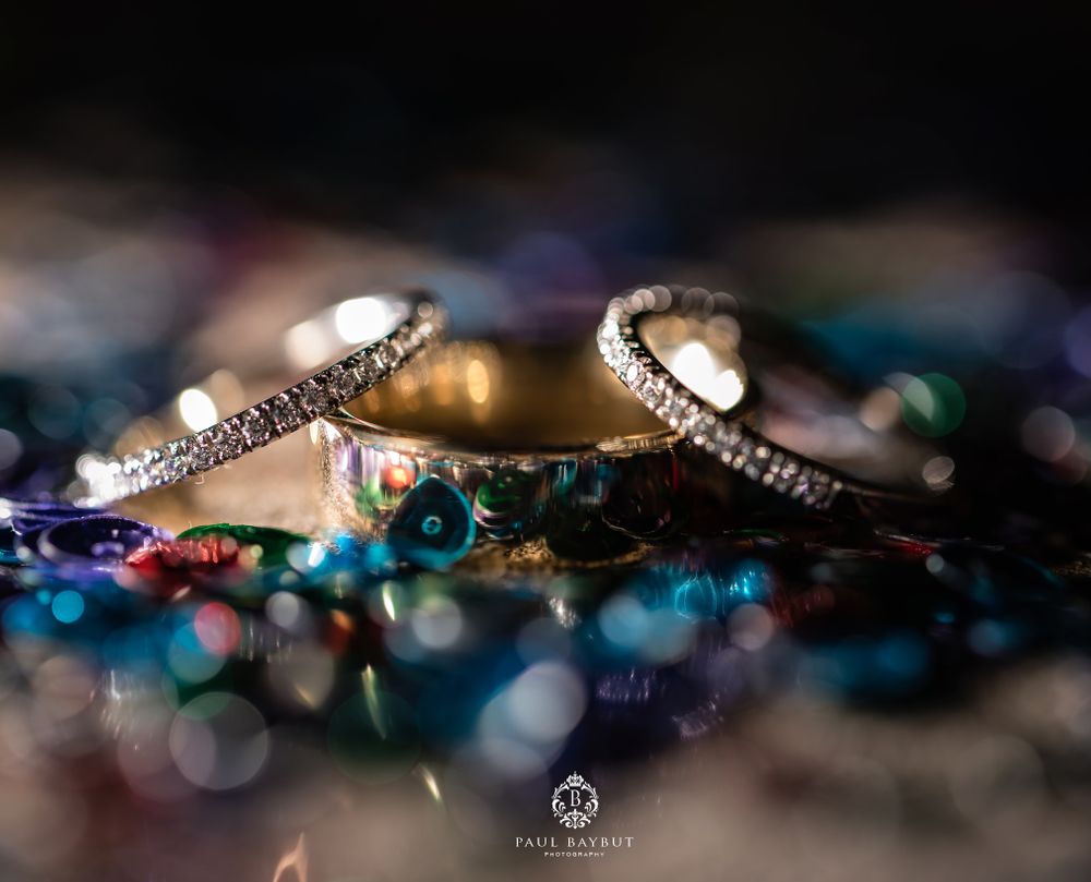 Wedding rings with diamond accents photographed on a surface with blue bokeh lights.