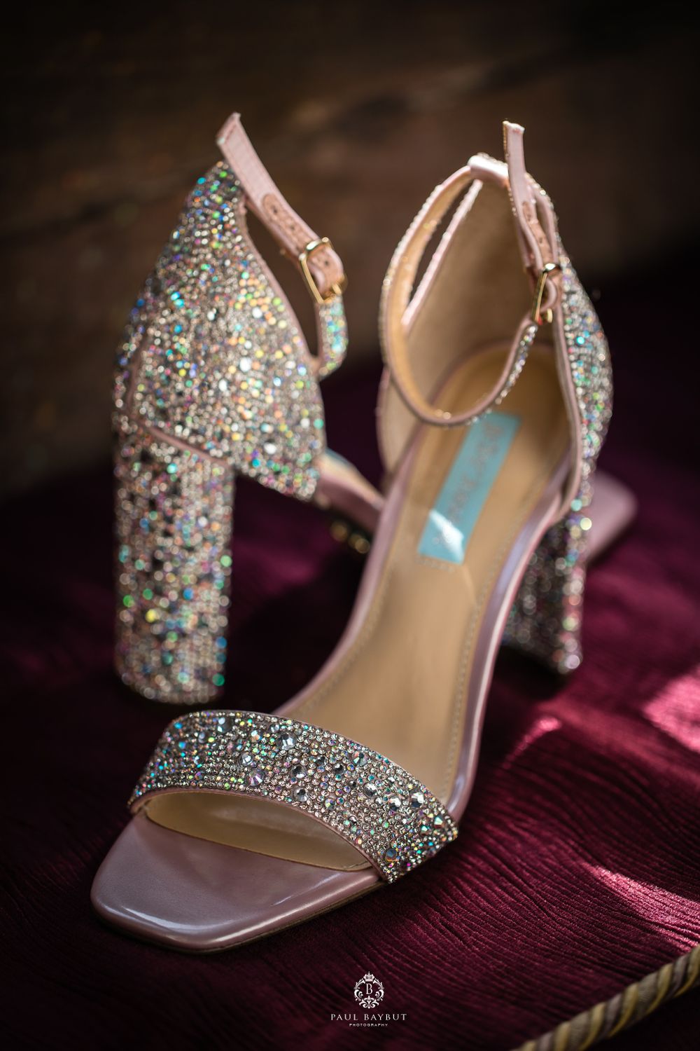 Sparkly silver crystal-encrusted high heel wedding shoes on burgundy velvet.