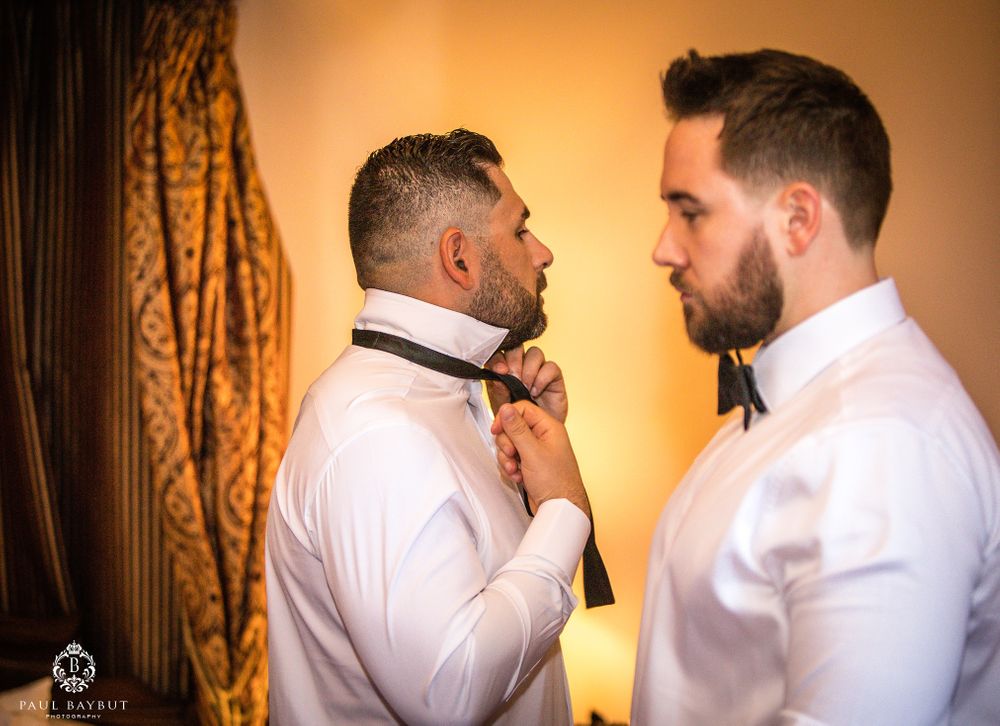 Two people adjusting bow ties in formal attire.