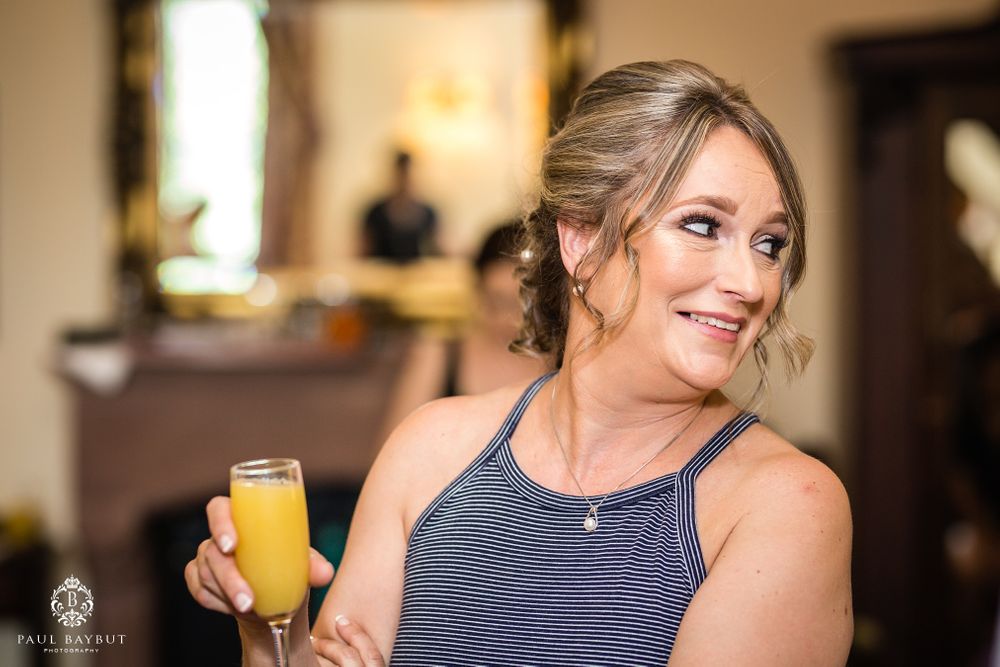 Person in navy sleeveless dress enjoys mimosa at formal event.