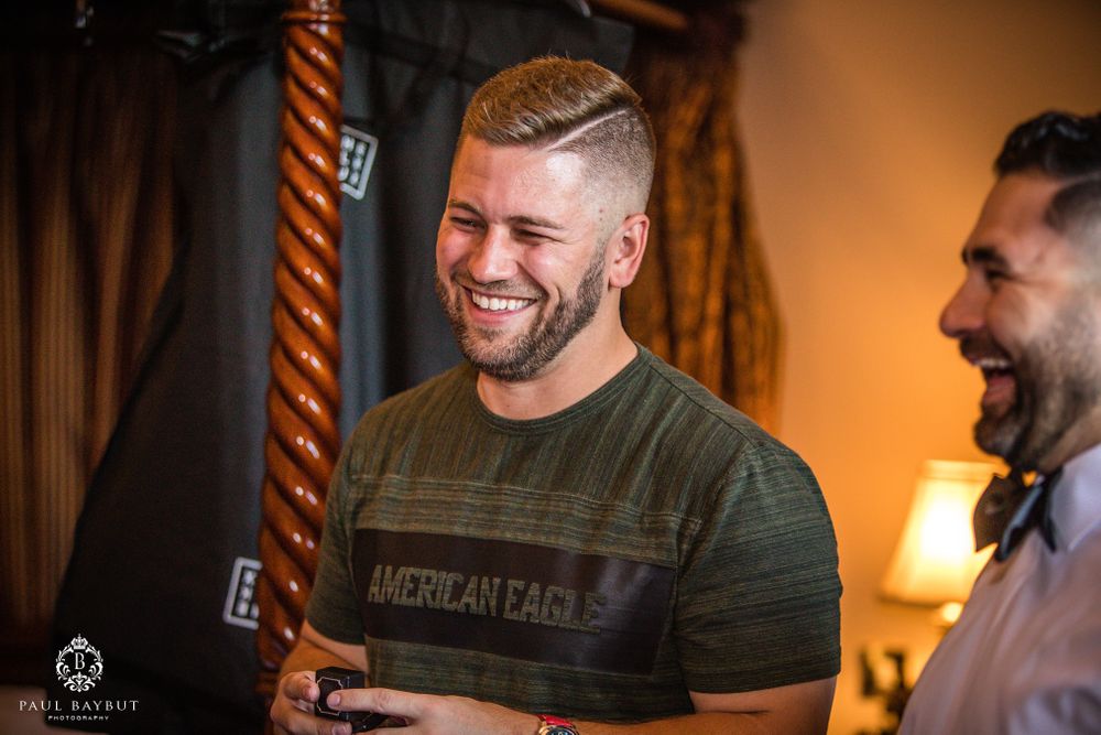 Man in green t-shirt shares authentic laugh during casual gathering.