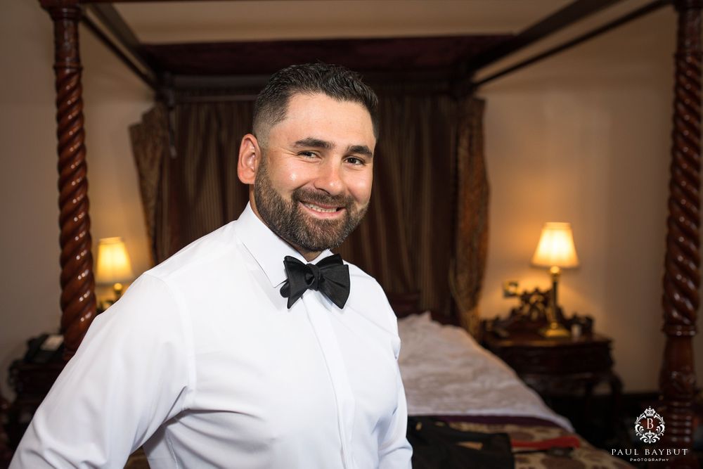 Well-dressed person in white dress shirt and bow tie smiles warmly at camera.