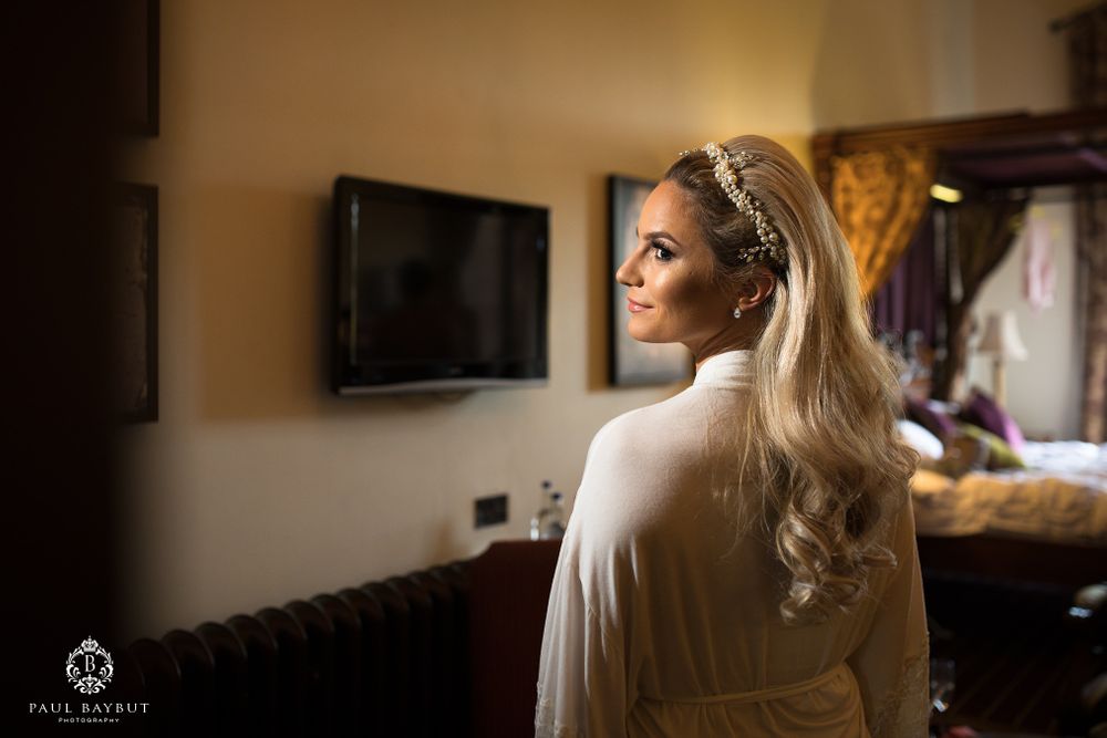 Profile view in a warmly lit room showing elegant hairstyling and white robe.