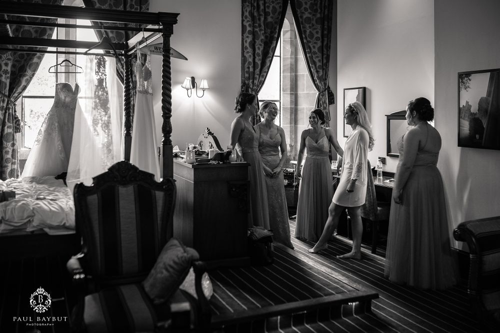Black and white photo of pre-event preparations in an elegant room with mirrors and curtains.