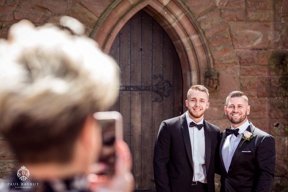 Someone taking a photo of two people in formal wear outside a gothic church door.