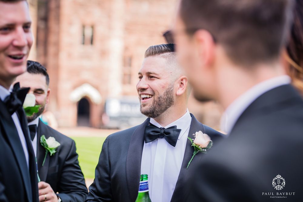 Wedding party enjoying drinks and laughter during outdoor celebration.