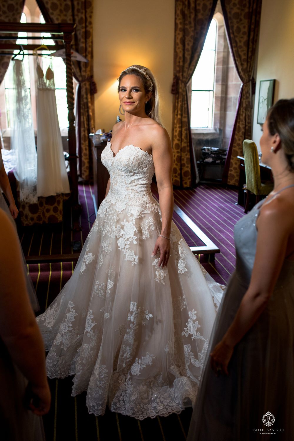 Stunning lace wedding gown displayed in elegant dressing room with natural lighting.