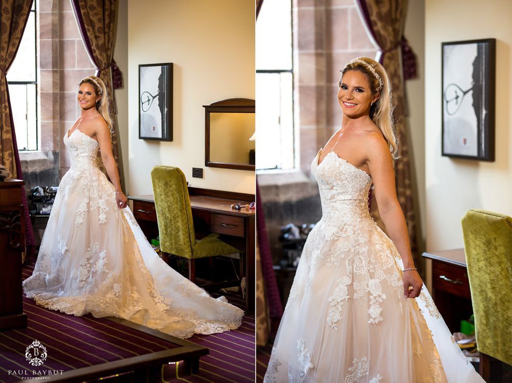 A strapless lace wedding dress with floral appliques and flowing tulle skirt showcased in an elegant interior.