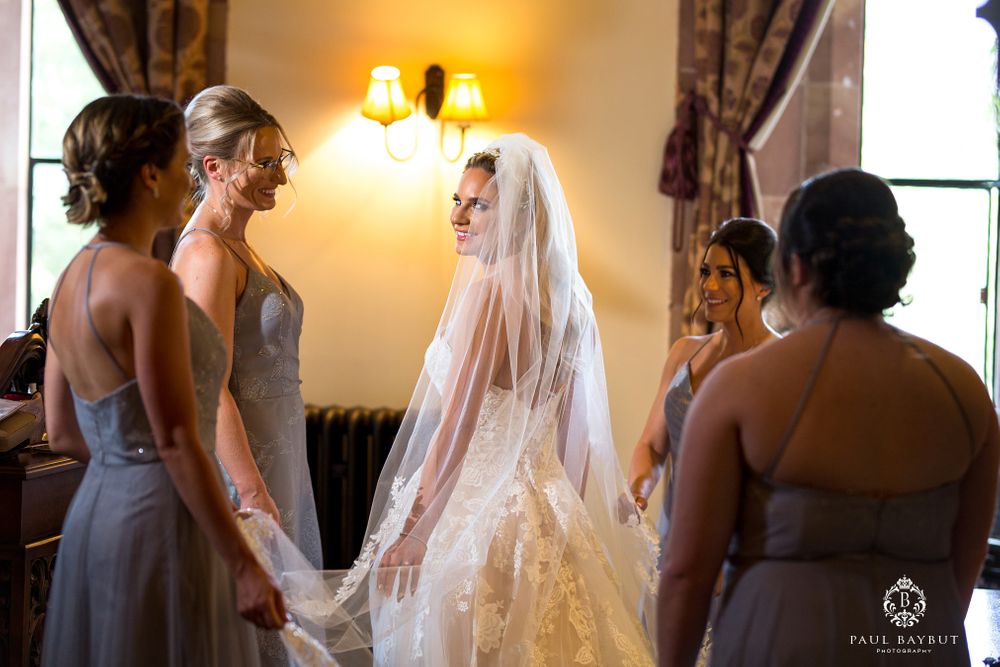 Bridesmaids in blue dresses gather around the bride during wedding preparations.